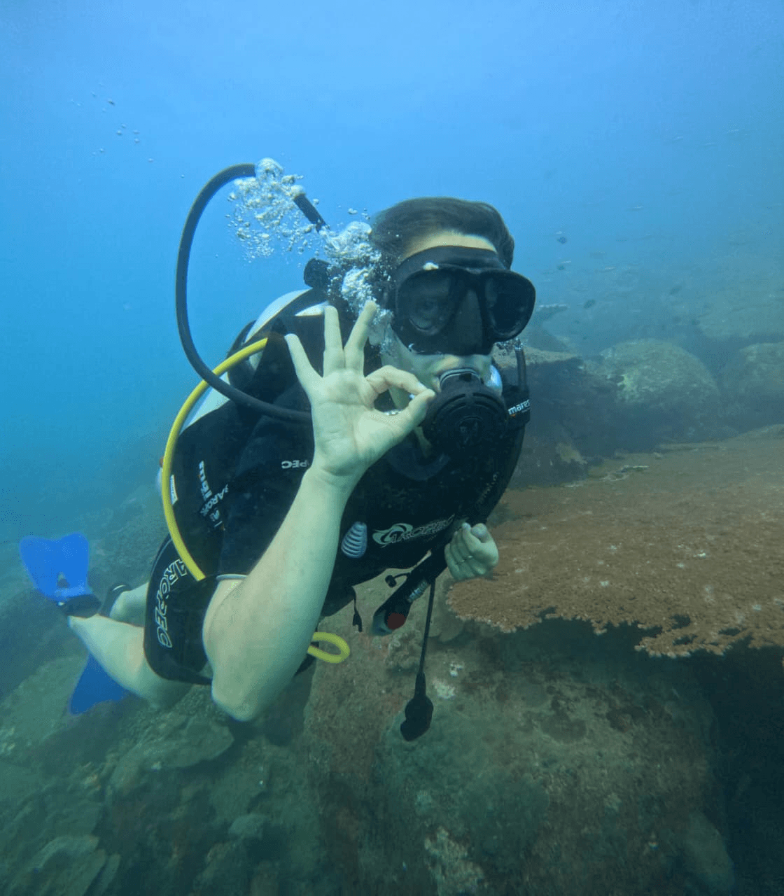 A first-time diver giving the OK hand signal underwater