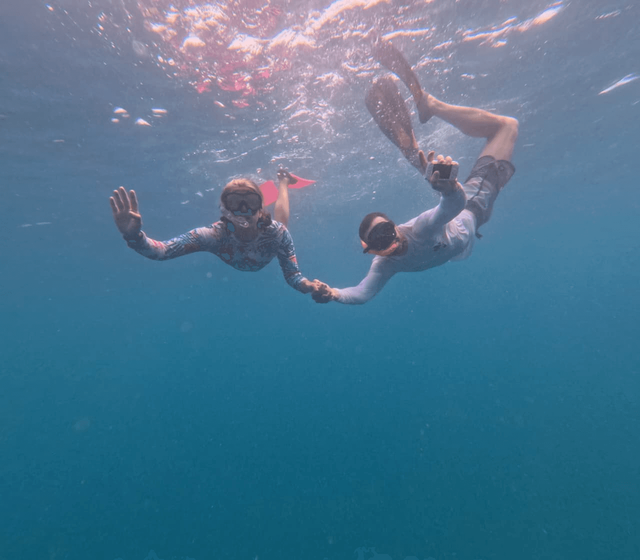 A couple snorkeling together, holding hands underwater